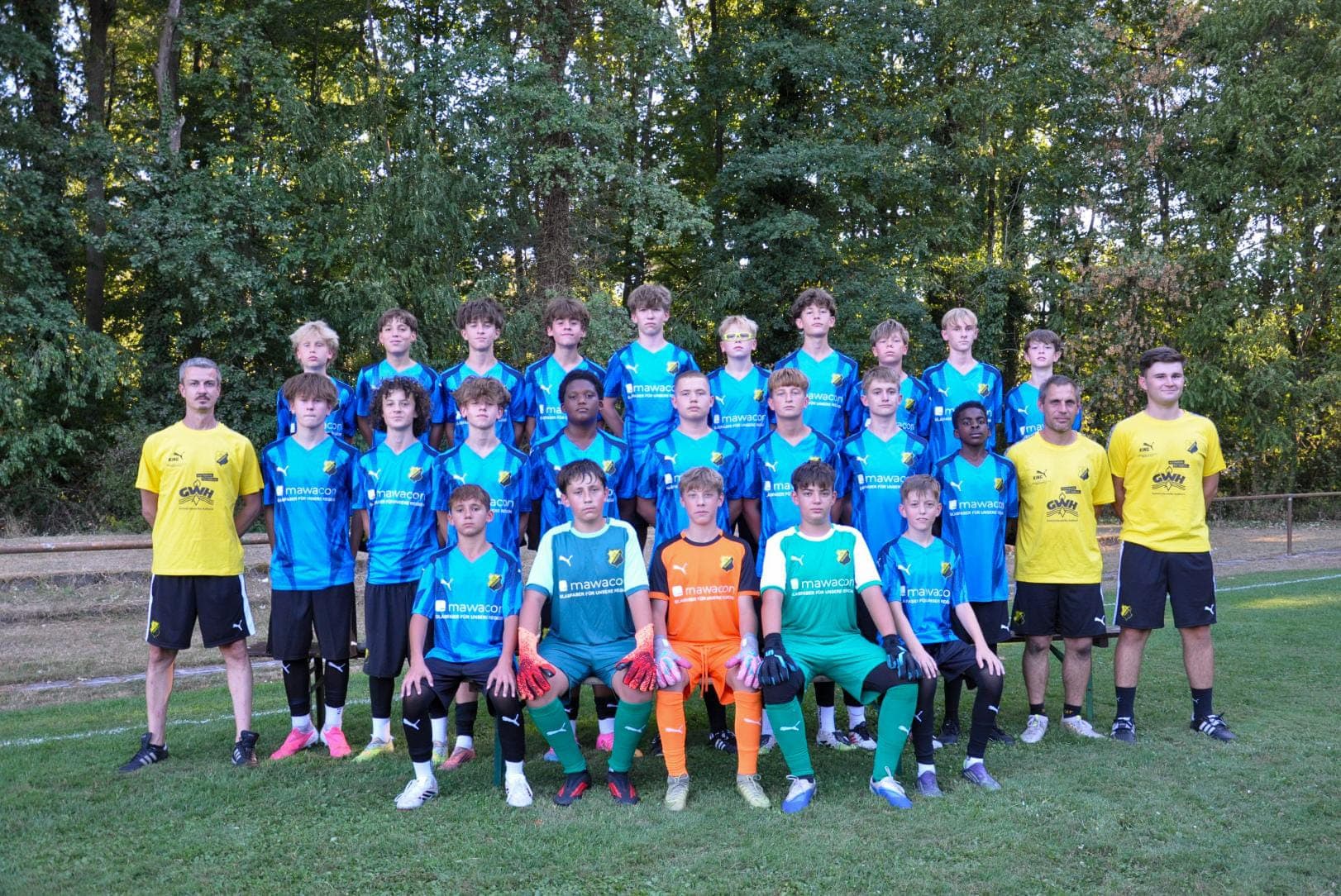 Jugendmannschaft aus Haßloch in hellblauen Trikots mit Mawacon-Aufdruck, daneben zwei Trainer in gelben Shirts